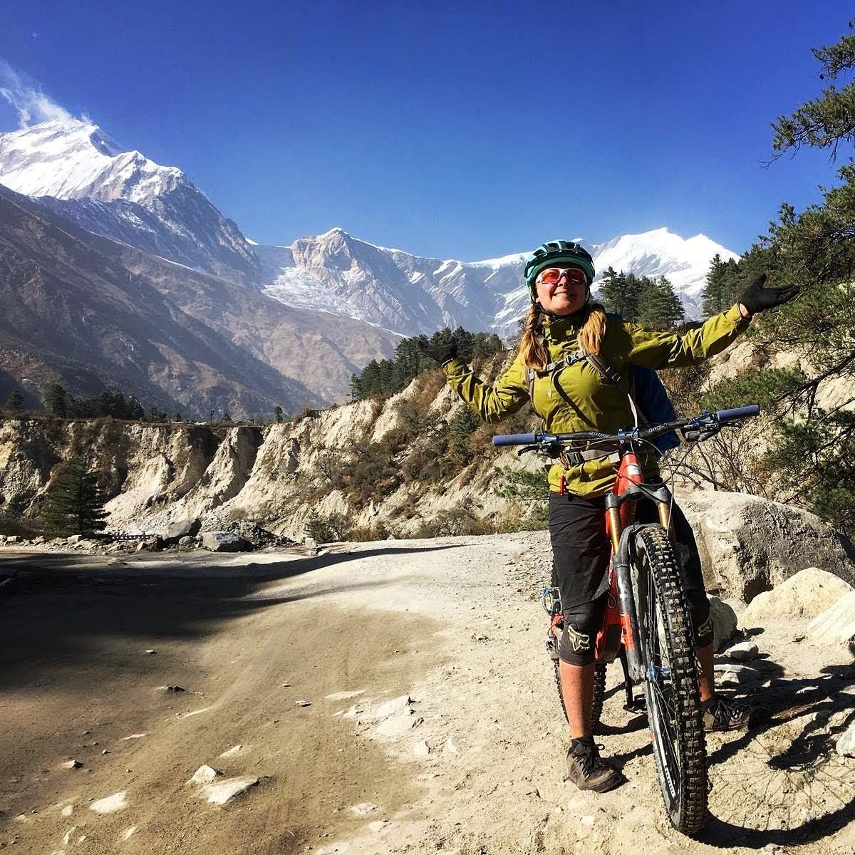 A mountain biker in green jacket expresses her happiness with the view of Dhaulagiri on the background.