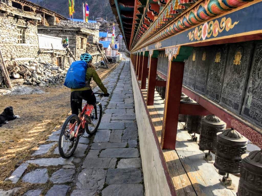 A mountain biker carrying a blue bag enjoys her rie alongside the mane wall in Pisang.