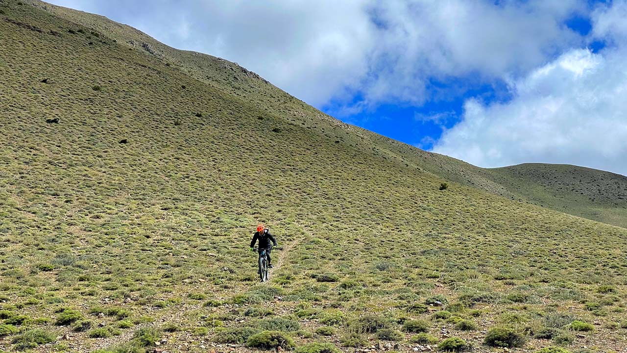 A mountain biker with orange colored helmet enjoys the downhill trail of Lupra in Mustang.