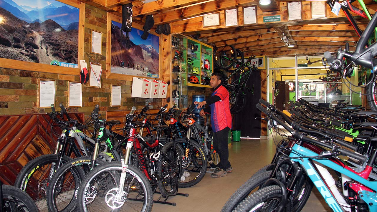 A man in red and blue t-shirt is checking the mountain bikes at the mountain bike shop of Pokhara Mountain Bike Adventure.