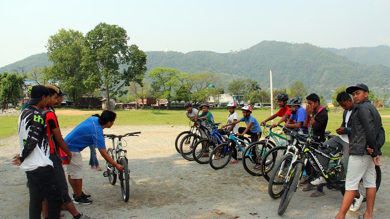 A mountain bike instructor is teaching kids and young boys about M-check at the camping ground in Pokhara.