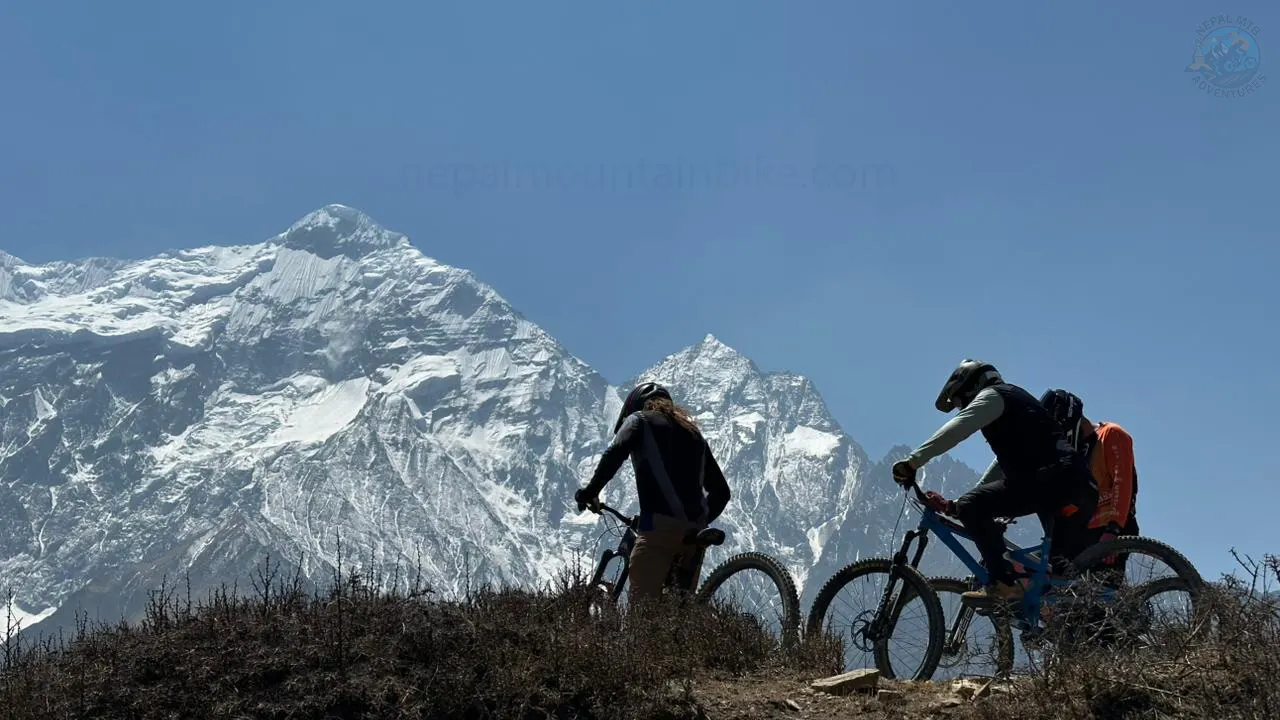 MTB riders are biking with the view of Nilgiri during Enduro mountain biking tour in the Himalayas of Nepal.