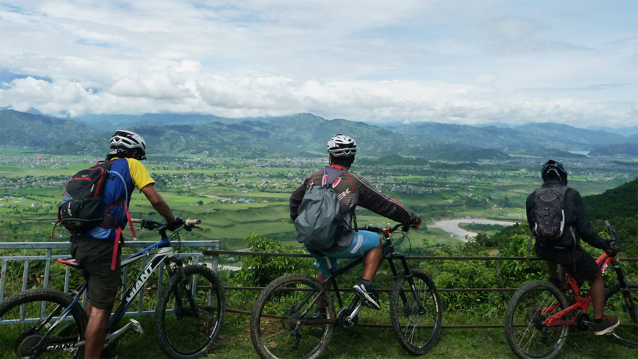 Three mountain bikers on their bike are enjoying the view of the valley.