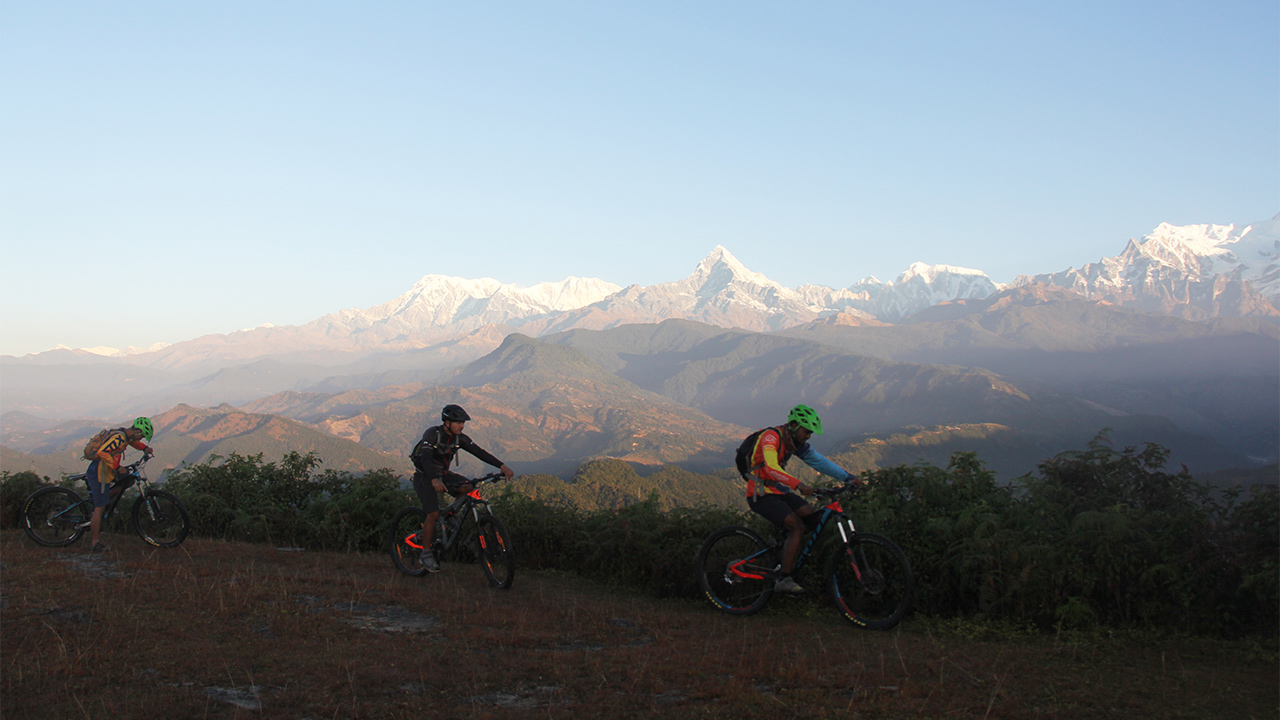 Three mountain bikers enjoying their ride with the view of Fishtail and Annapurna mountain range.