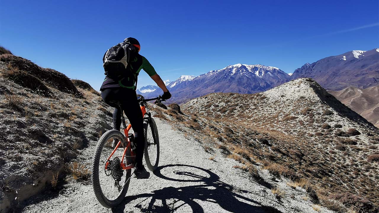 a mountain biker on orange colored mountain bike is enjoying his ride in Upper Mustang