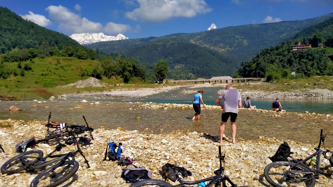 mountain bikers are enjoying their swim in Harpan river with the view of Mt. Fishtail