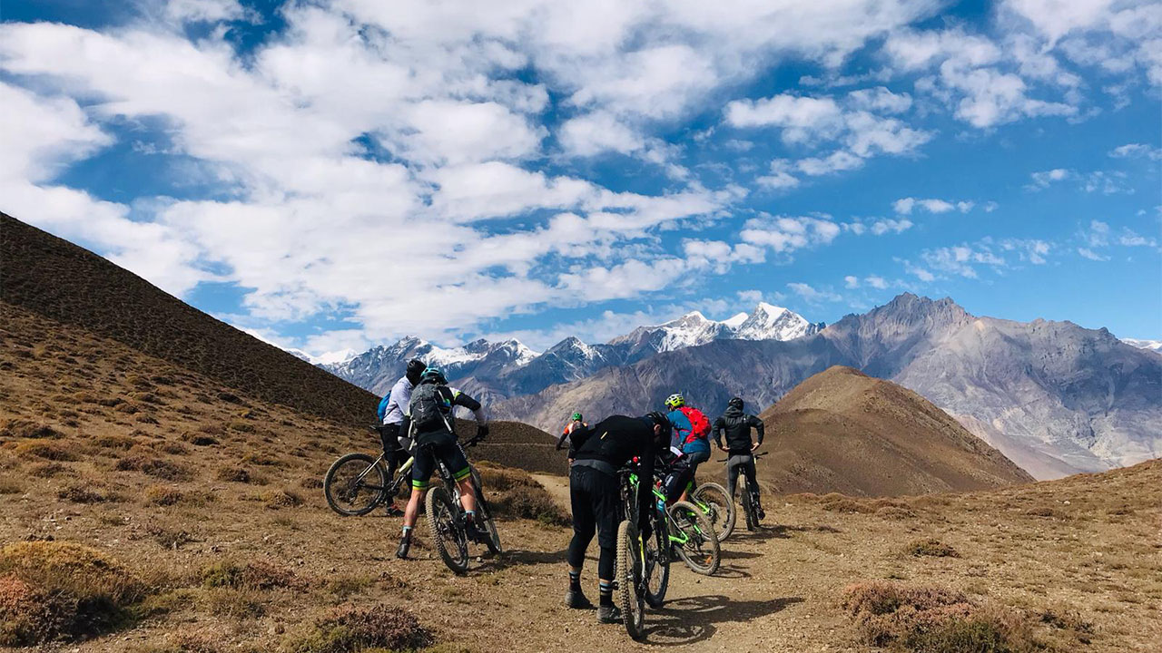 Seven mountain bikers getting ready to ride the best single tracks of Mustang, Nepal and the view of Dhaulagiri seen on the far back