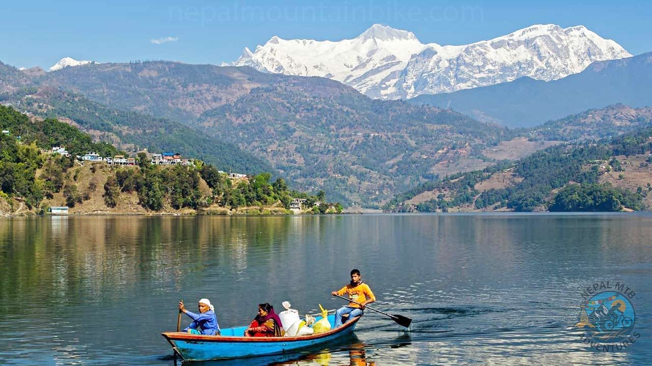 People are rowing the boat across Phewa Lake with their supplies in the sack. 