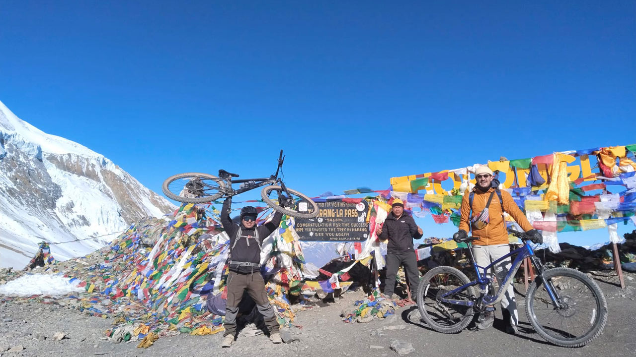 Mountain bikers are taking picture on the top of Thorong-La Pass during the Annapurna Circuit mountain bike tour.