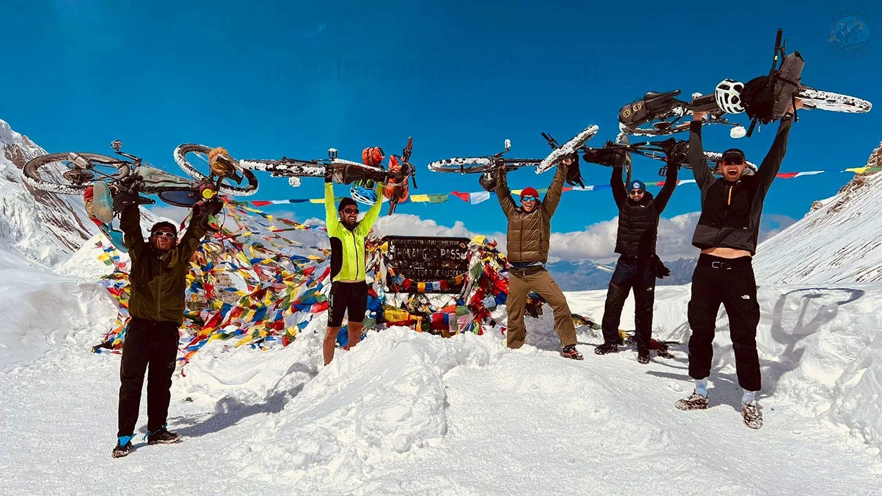 Mountain bikers are taking picture on the top of Thorong-La Pass during the Annapurna Circuit mountain bike tour.