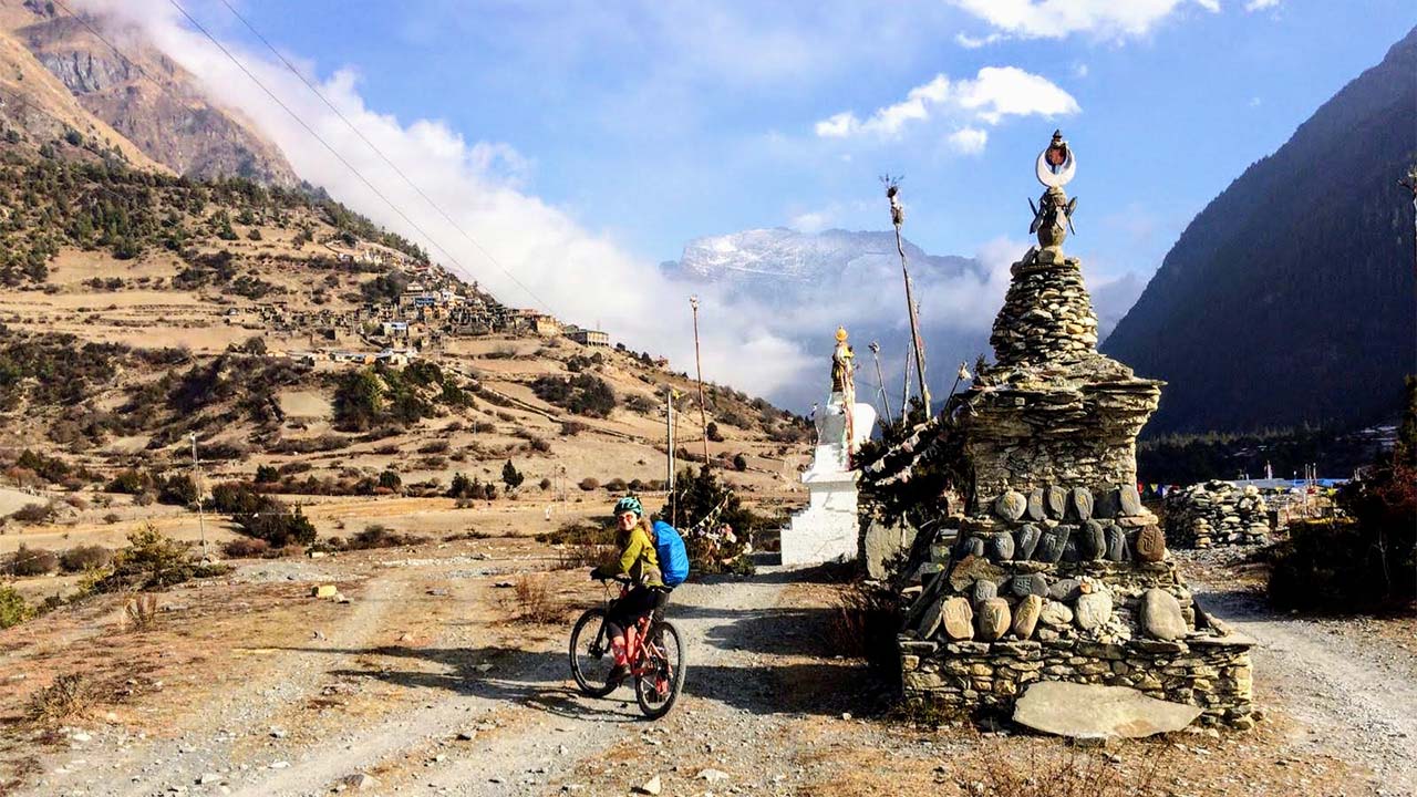 A women on her mountain bike is ready to get her picture clicked with the view of Upper Pisang village.