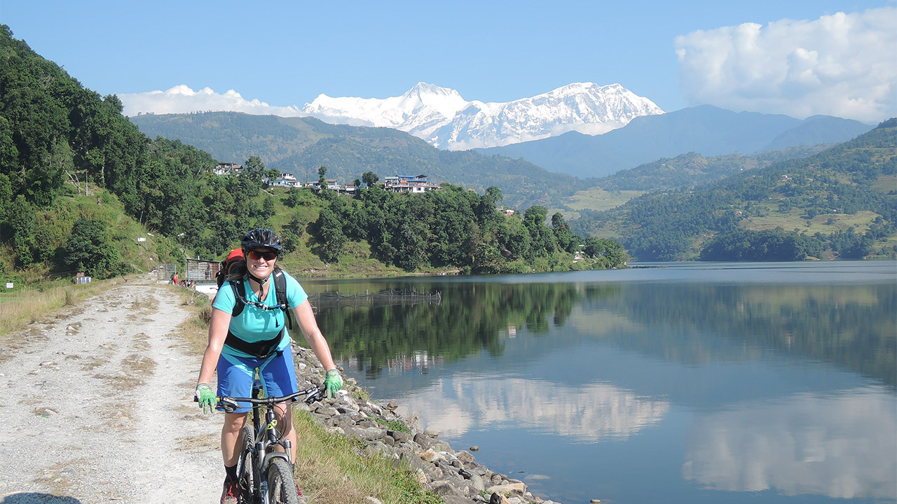 A women in blue outfit is riding her bike along the Begnas Lake Shore in Pokhara.