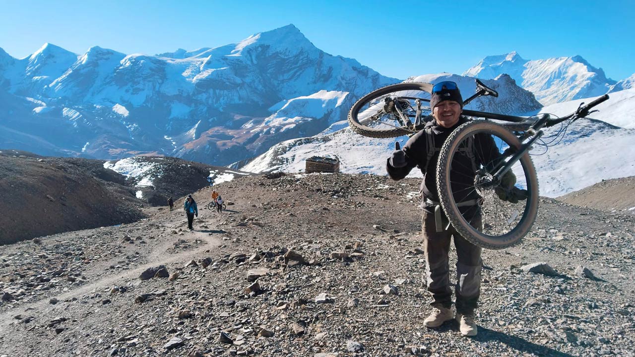 Cyclist carrying mountain bike up to Thorong-La pass, the highest point on the Annapurna Circuit at an altitude of 5416m.