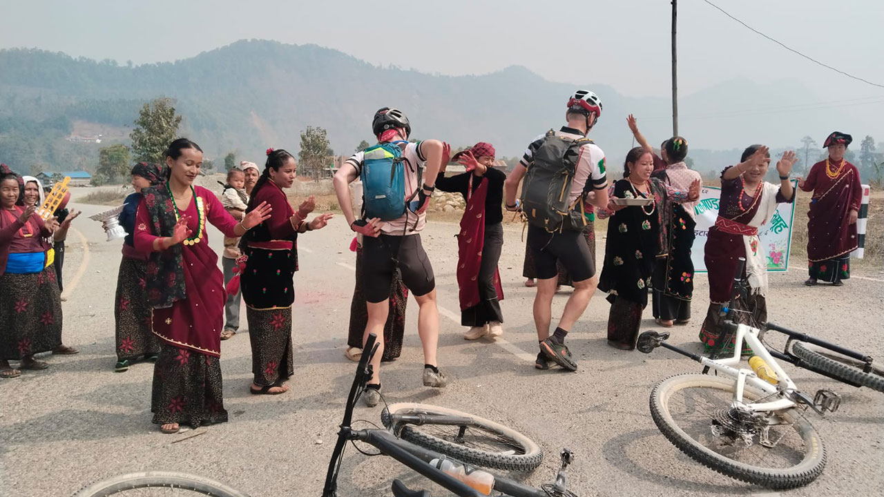 Mountain bikers participating in a local cultural dance during their mountain bike tour in Nepal.