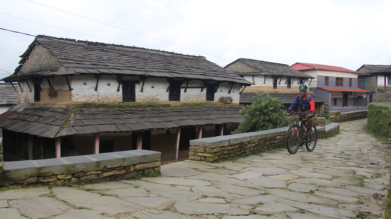 A mountain biker is riding his bike through Gurung village of Dhampus.