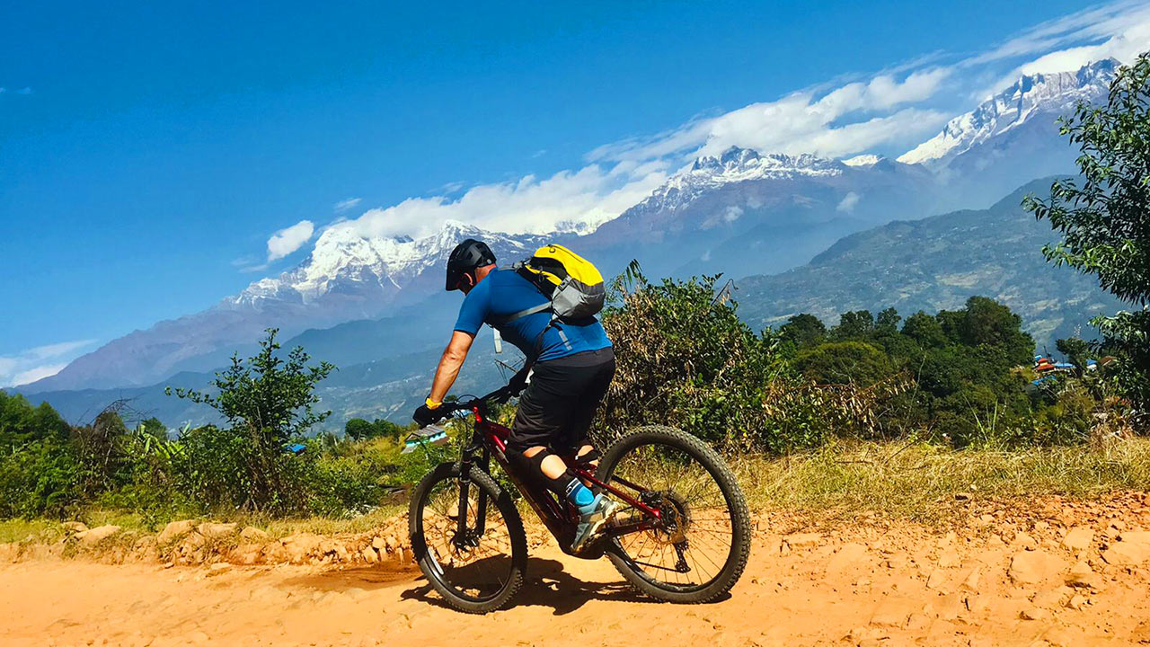 A biker is rolling down towards Pokhara on his E-Bike with the beautiful view of Fishtail and Annapurna South.