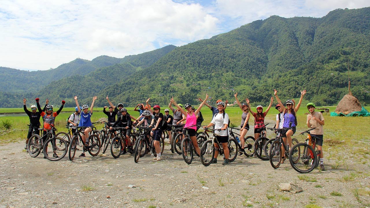 Group of mountain bikers are cheering raising their hands in the air to take picture during their easy mountain bike tour in Pokhara.