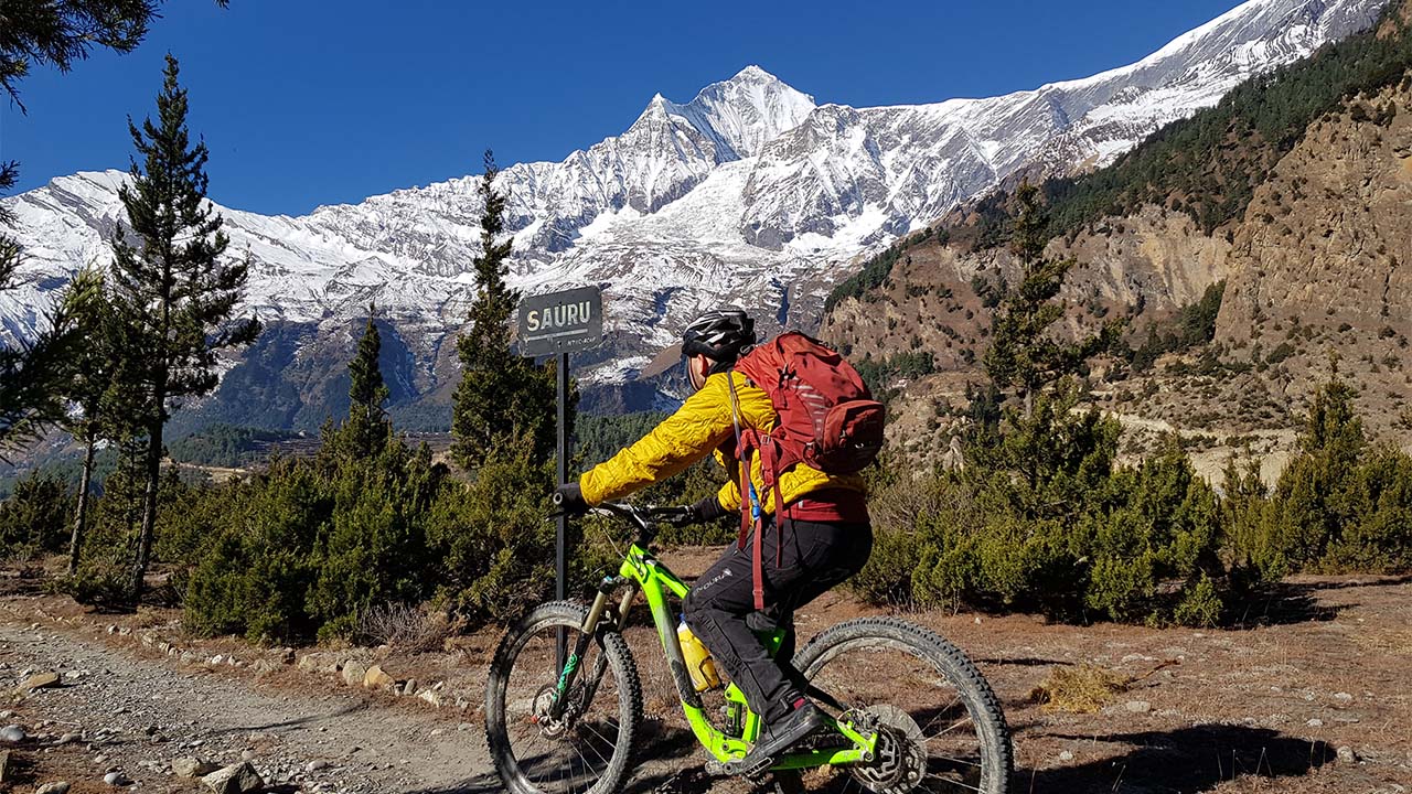 A mountain biker enjoys his ride through the incredible trail and view of Dhaulagiri in Mustang.