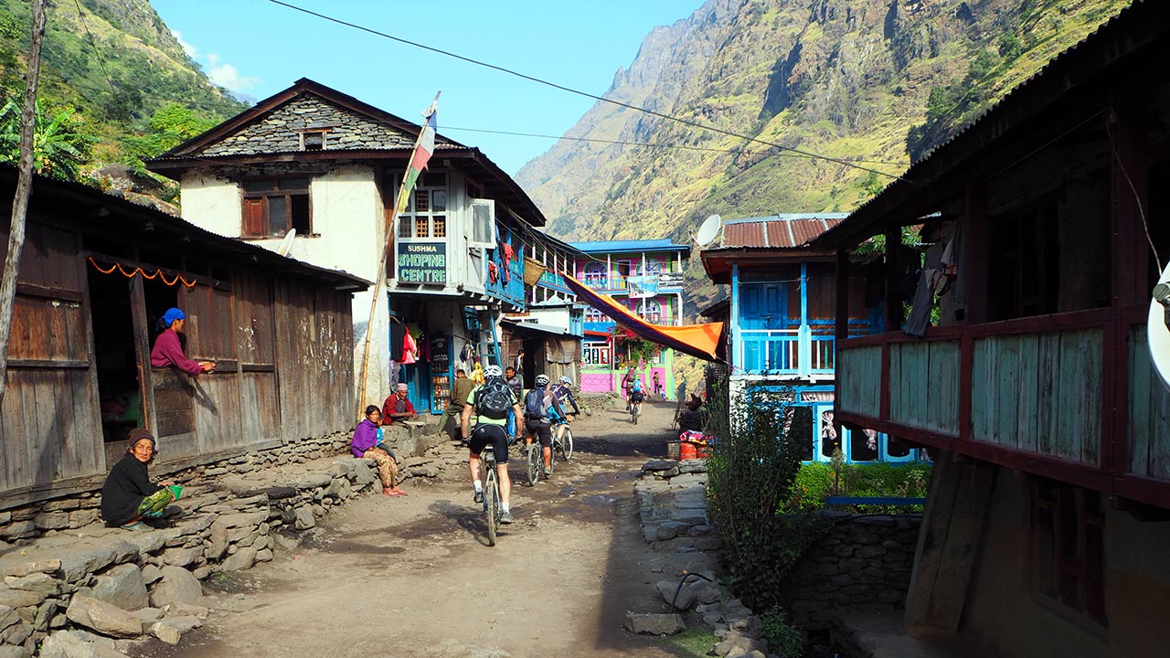 A group of mountain bikers are riding their bikes inside the Chyamche village road while the local people are observing in surprise.