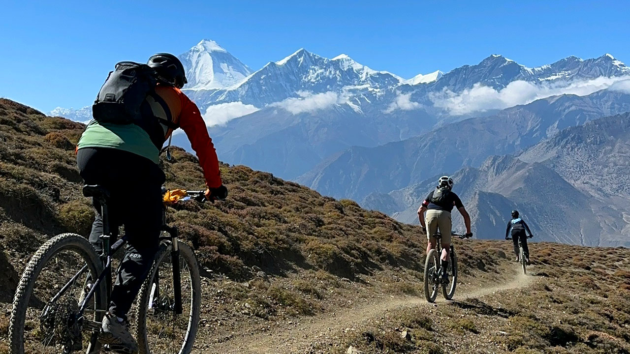 A group of bikers are riding through the Lupra single trail with the view of Dhaulagiri Himalayan range in Lower Mustang region.