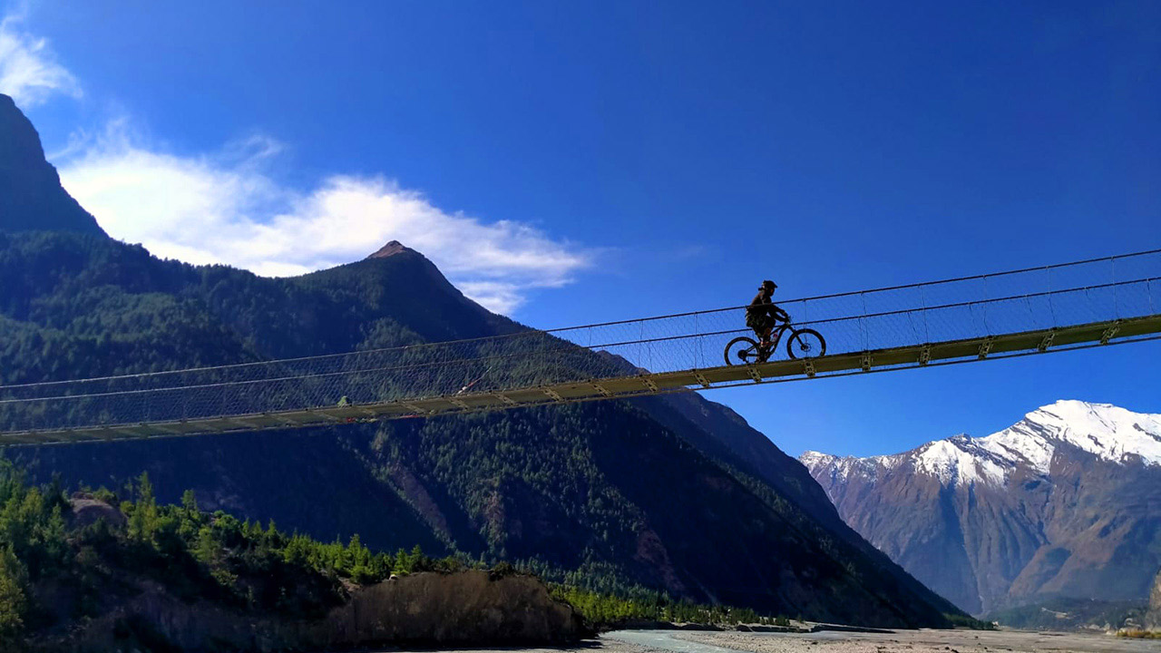 A mountain biker rides the bike over the suspension bridge in Mustang during the Annapurna MTB tour.