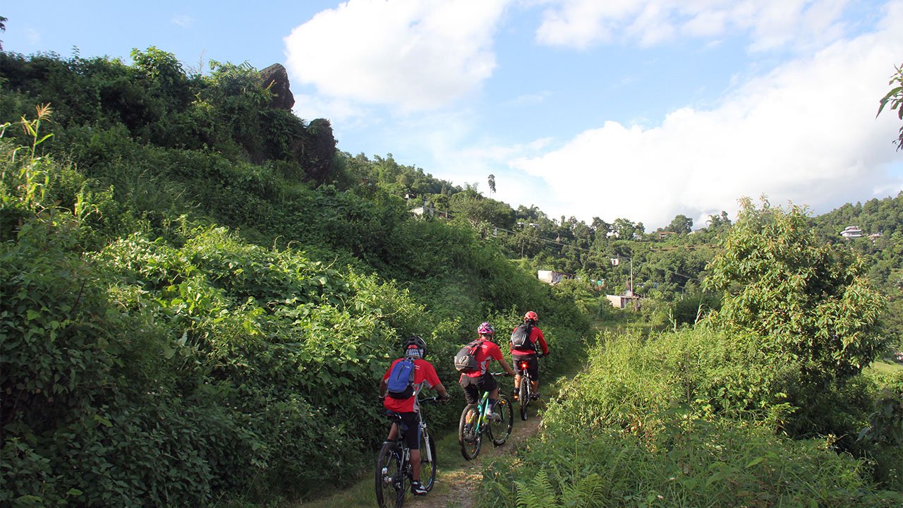 Group of mountain bikers all of them in red T-shirt are pedaling through single track while heading to Sarangkot in Pokhara.