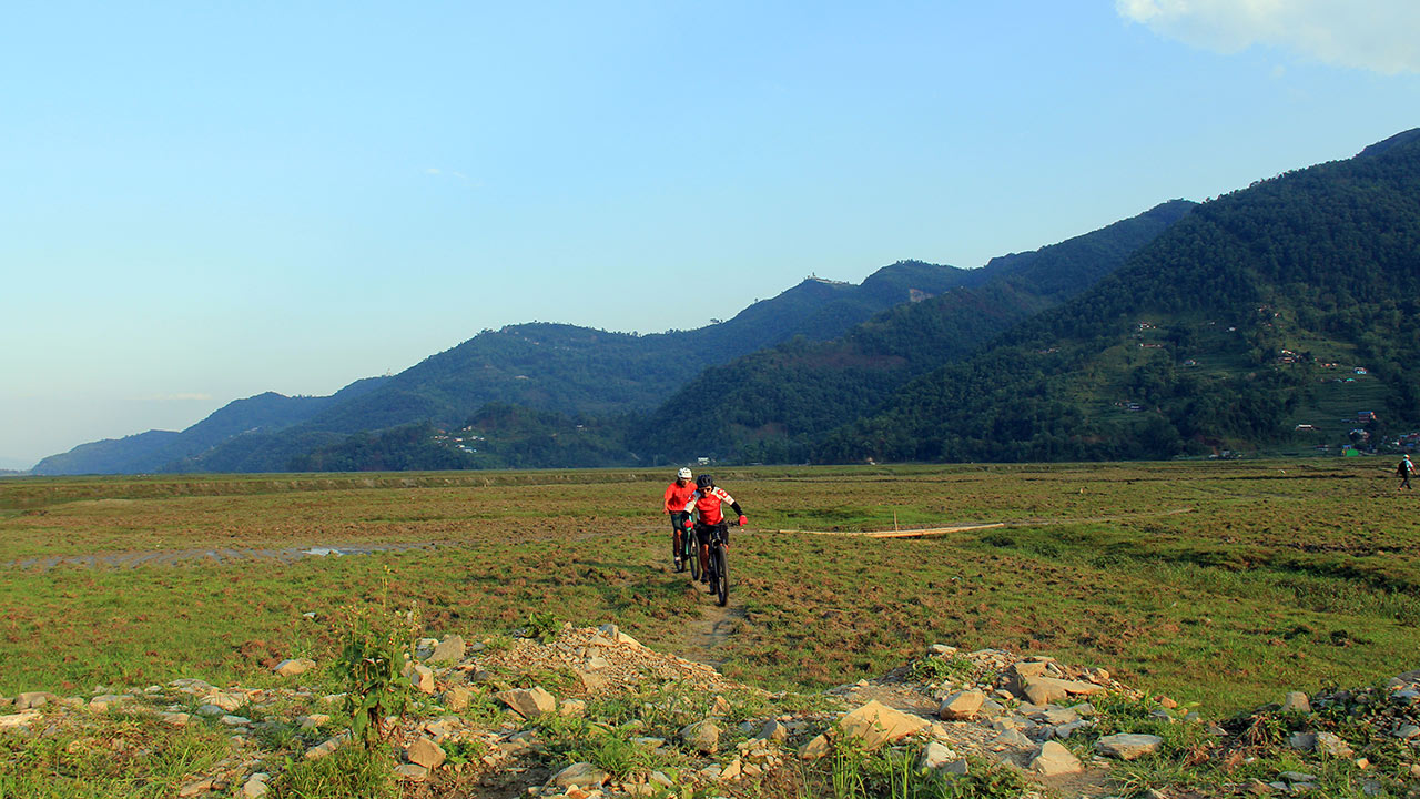 E-bikers riding through the paddy fields in Pokhara during Nepal E-MTB Tour.