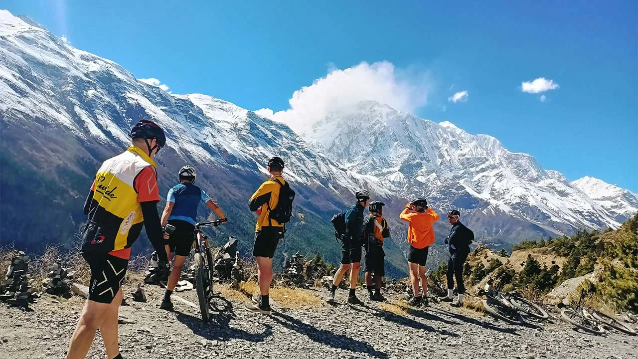 Group of MTB riders observing the Himalayas during Annapurna Circuit mountain bike tour in Nepal.