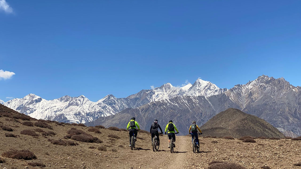 A group of mountain bikers cherishing the ride through Lupra single trail in Mustang with the view of the Himalayas.