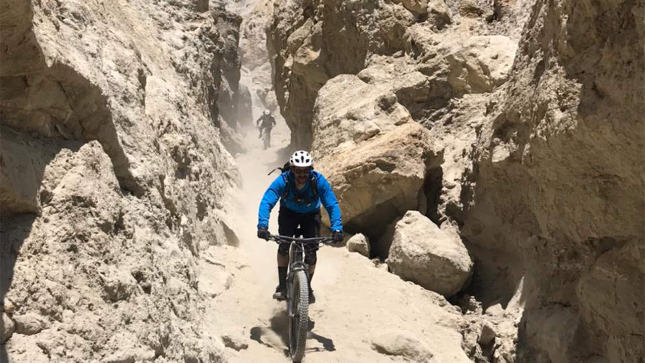 A mountain biker in Yellow and Black is heading towards Lo-Manthang in Upper  Mustang.