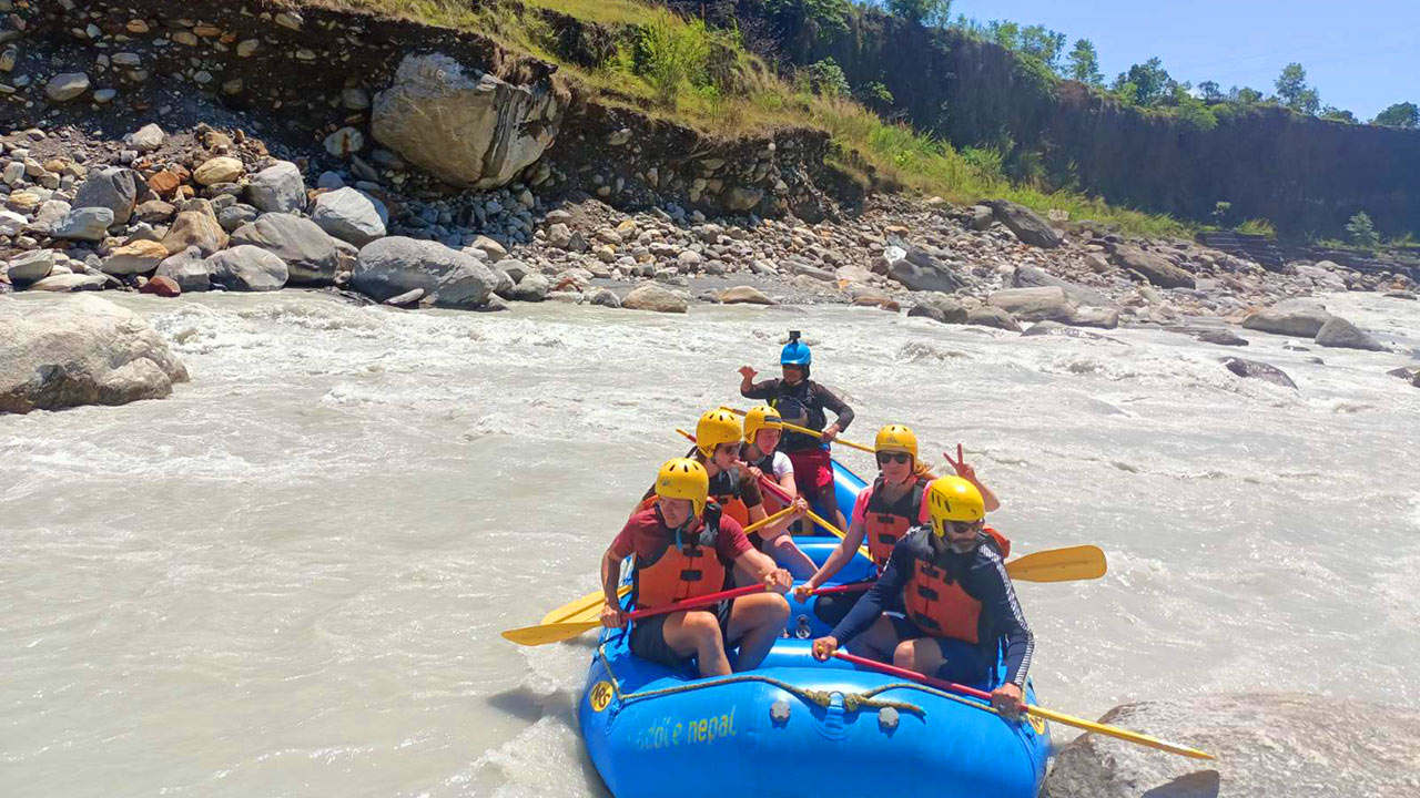 A group of people are sailing on the raft in the white water of Seti River.