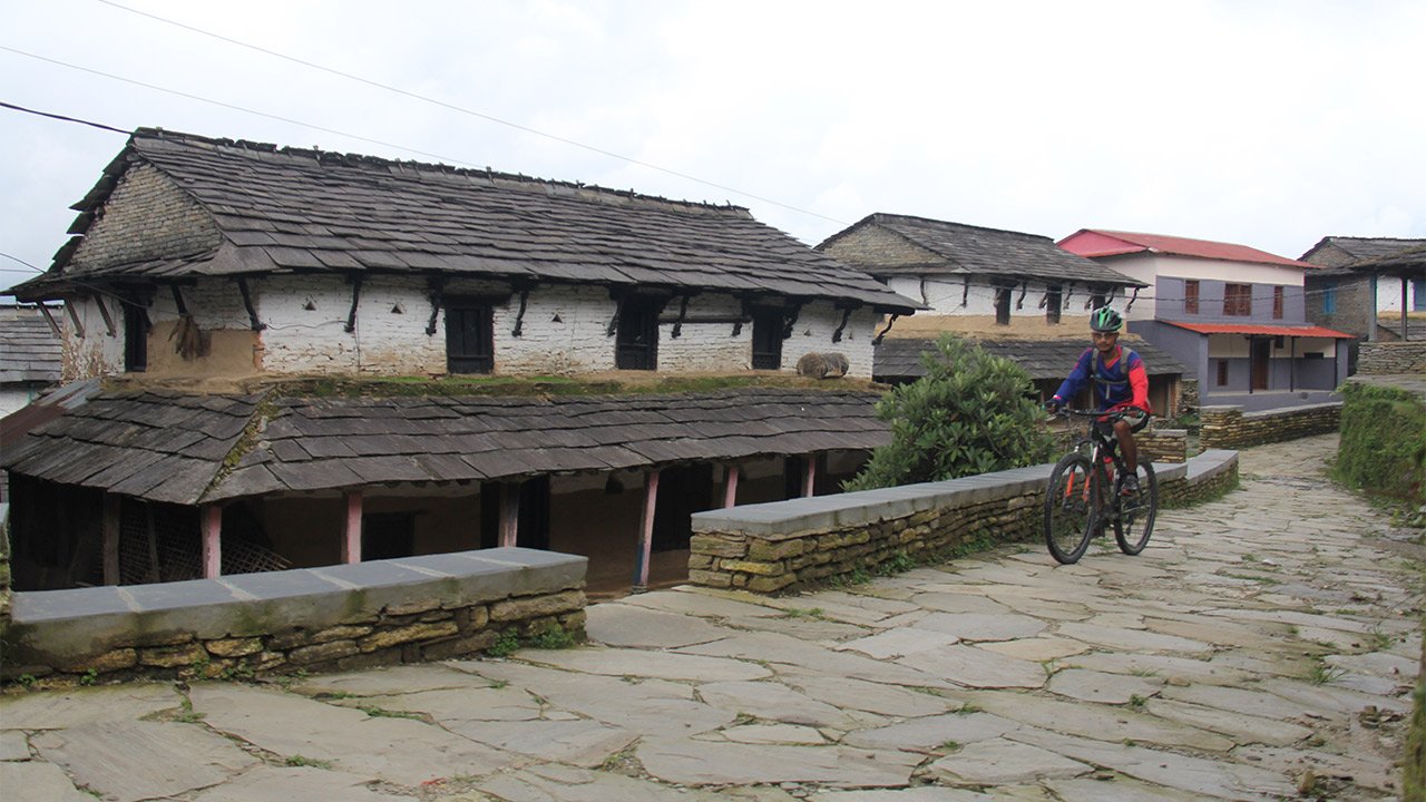 A biker rides his mountain bike through Gurung village in Dhampus.