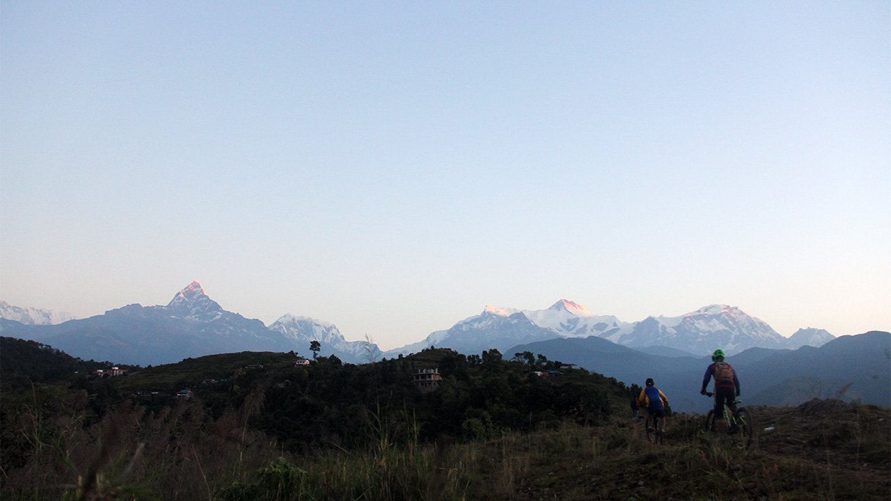 Two mountain bikers are biking along the ridge with the view of the Annapurna mountain range near Sarangkot.