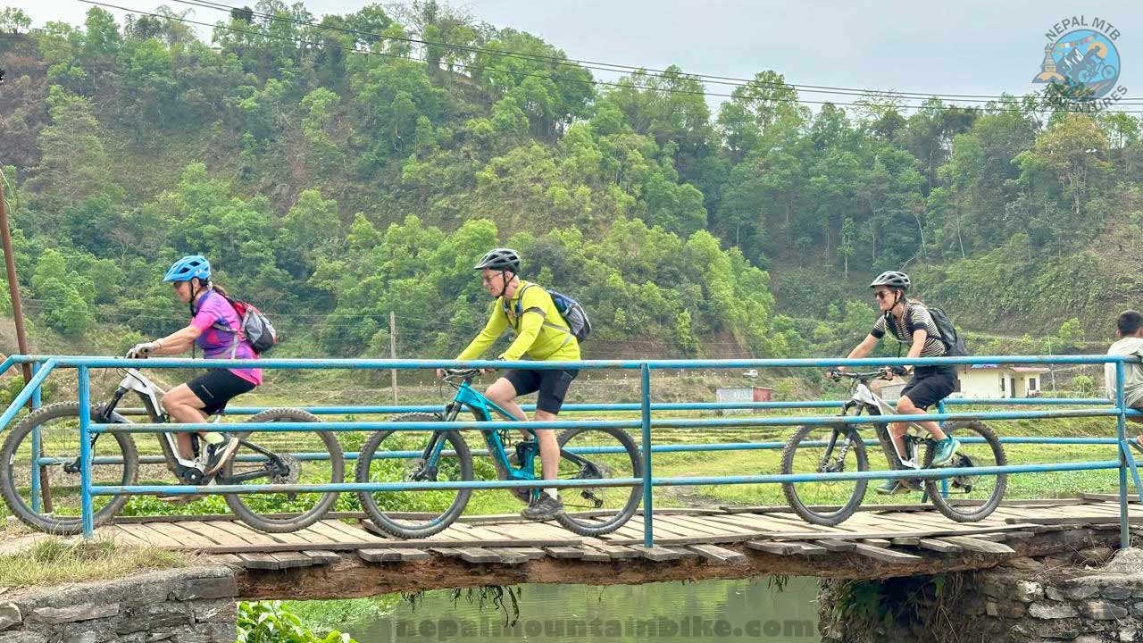Electric mountain bikers crossing the wooden bridge during Nepal E-MTB guided tour.