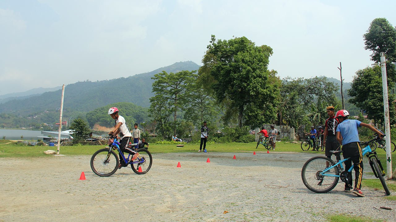 Kids are testing their maneuvering skill riding through cones during their mountain bike class in Pokhara. 